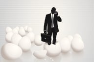 Dark man in suit and tie with briefcase stands on broken egg shells