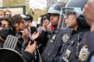 Students face to face with a line of New York City police in riot gear.