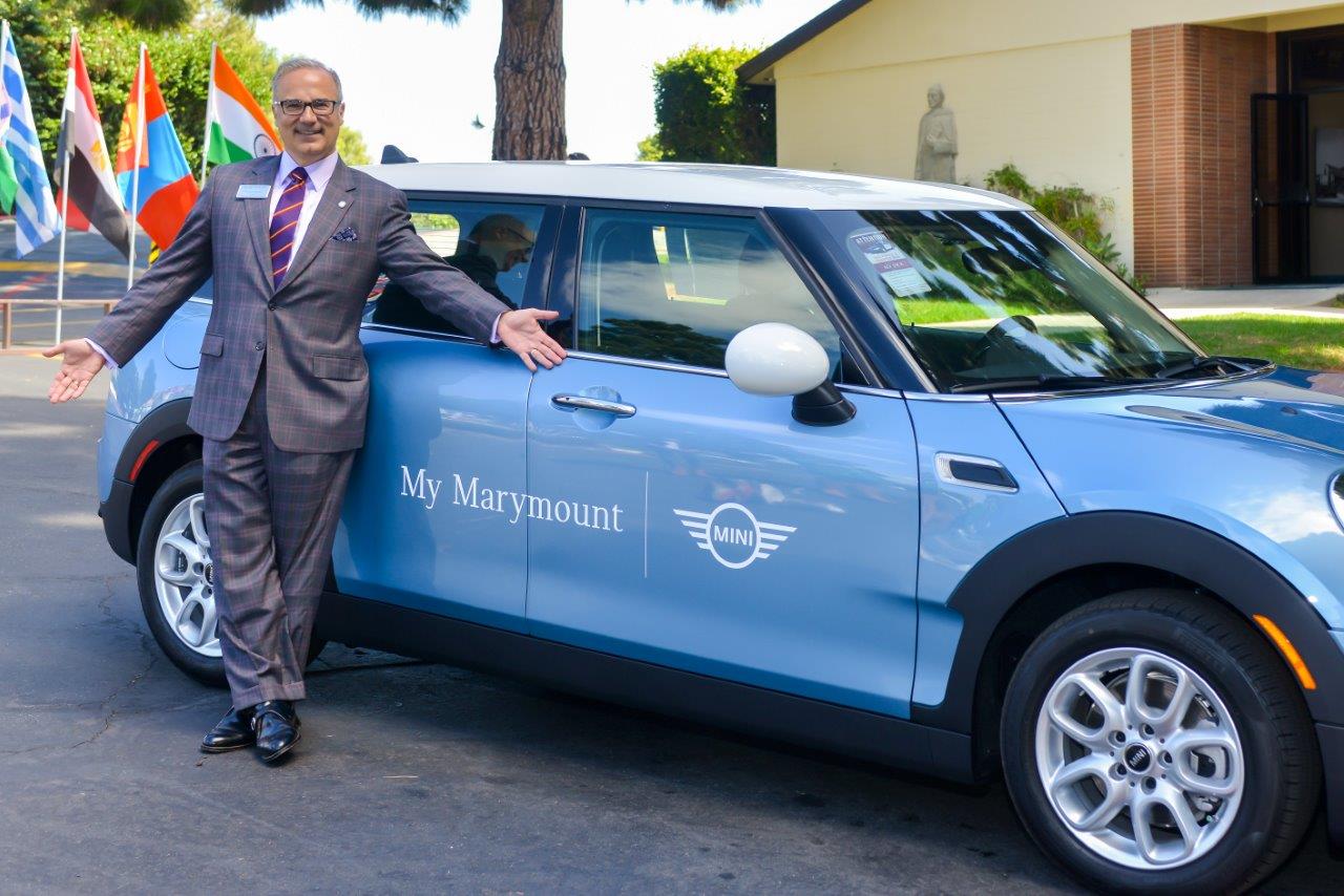 Former Marymount California president Lucas Lamadrid poses with a Mini Cooper automobile as part of the "My Marymount Mini" program announced in 2016.