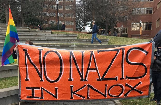 Photo of orange banner saying "No Nazis at Knox," next to a rainbow flag.