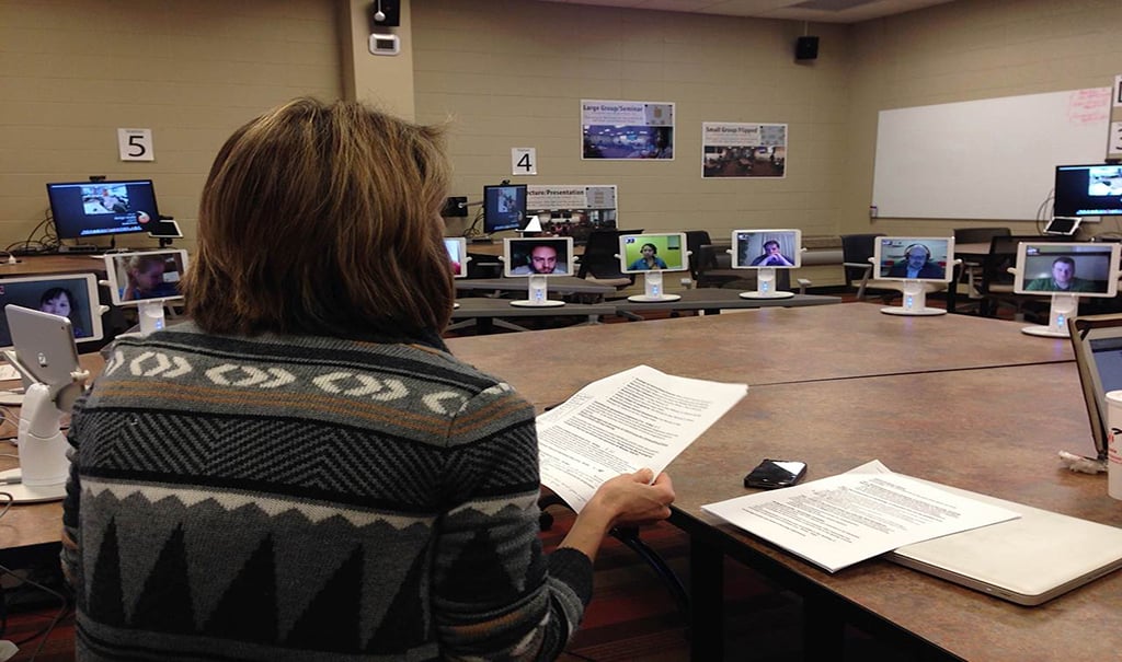 Image of Christine Greenhow in her classroom, surrounded by iPads enabling students to participate remotely.
