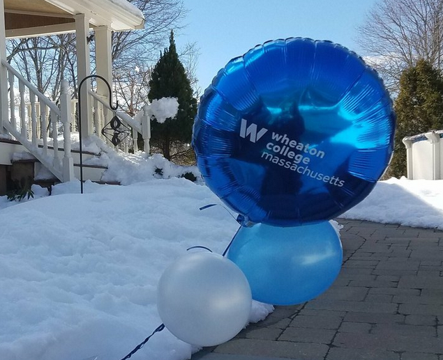 Image of a front porch surrounded by snow and blue Wheaton College Massachusetts balloons.