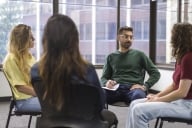A group of college students sit in a circle during group therapy.
