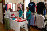 Two student employees assist a student in selecting clothing items from the free clothing store on Wittenberg University's campus.