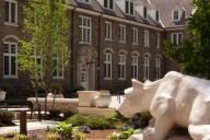A photograph of a statue of the Penn State Nittany Lion mascot looking toward a building on campus.