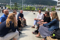 Babson and Nord leaders sit talking on wooden benches on a sunny day in Norway.