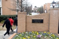 Three students walk past a plaque on a brick wall that reads "Morehouse College, founded 1867."
