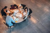 A group of students study around a round table in a library