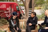 A student talks to two professionals with the University of California, Davis, Fire Department on a bench in front of a red van