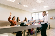 Teacher giving advice to diverse university students in classroom
