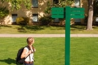 A college student looks a the sign for direction.