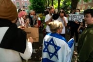 A person wrapped in an Israeli flag at a protest in George Washington University
