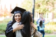 After her graduation ceremony, the young adult daughter closes her eyes as she embraces her unrecognizable mother.