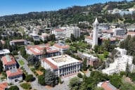 An aerial drone view of the University of California, Berkeley campus shows buildings and trees near a hillside
