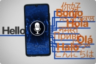 A large gray word “Hello” is on the left side of the screen. A cell phone is in the middle with a microphone icon that has “AI” on it. On the left side, numerous versions of the word “Hello” in different languages appear in orange