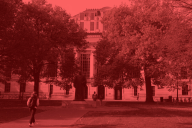A student walks on a college campus, but the image is entirely red and black 