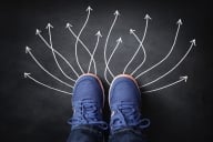 Arrows symbolizing different pathways jet out from a close-up of a student's pair of blue sneakers (concept image).
