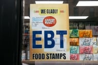 A yellow sign that says We Gladly Accept EBT Food Stamps hangs in a window