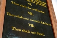 A chalkboard-like surface displays three of the Ten Commandments—"VI Thou shalt do no Murder, VII Thou shalt not commit Adultery, VIII Thou shalt not Steal."