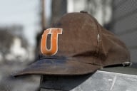 A scuffed baseball hat bearing the letter "U" for university