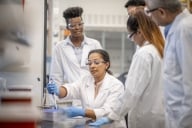 Woman showing chemistry students in a lab how to use a piece of equipment