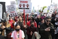 A photograph of a crowd of protesters, some holding signs bearing the name of the Massachusetts Institute of Technology Graduate Student Union.