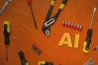 A scattering of yellow and black tools on an orange background accompanied by the letters AI