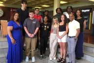 A group of students and staff members smile for a photo