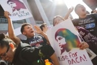 Students hold signs that read "Rise for DACA."