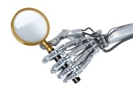 Robot hand holds magnifying glass as if to look closely and assess something