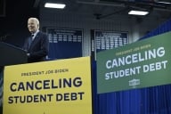 President Biden stands on a stage surrounded by two signs that say "President Joe Biden Canceling Student Debt."