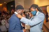 Calvin Hadley adjusts a student's tie at the You Lead tie ceremony. 