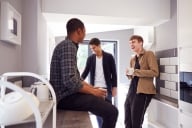 Group of male college students in shared house with hot drinks in kitchen hanging out together