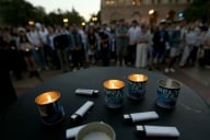 Candles and lighters are seen in the foreground while individuals stand in the background.