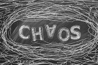 A black-and-white illustration of the word "Chaos," with the A upside down, surrounded by a messy doodle amounting to tangled lines.