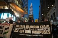 Protesters marching at night in New York City hold a big banner that says "Release Mahmoud Khalil/Hands Off Our Students/ICE Off Our Campuses/Shut It Down 4 Palestine."