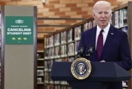 Joe Biden stands at a podium in front of bookshelves and a green sign that says Canceling Student Debt