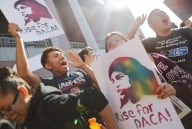 Students hold signs that read "Rise for DACA."