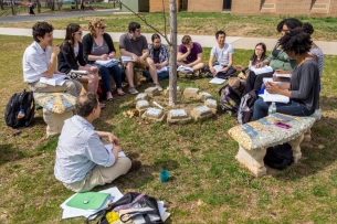 Students gathered around a spindly tree outside.