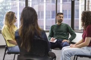 A group of college students sit in a circle during group therapy.