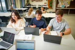 Three students work at open laptops.