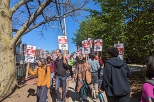 Rutgers University community members holding signs and striking. 