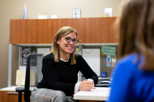 Mary Ann Tietjen, a light-skinned woman with blond hair, of Creighton University works with a student in her office.