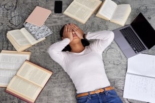 High angle shot of an unidentified young female student looking stressed while studying in the library - stock photo