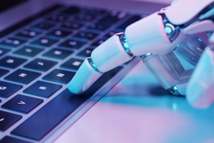 A robotic hand touches keys on a computer keyboard