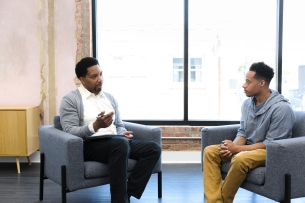 A male counselor speaks with a young male client.