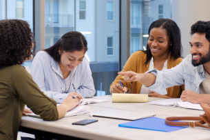 A group of students sits in a study room working together.