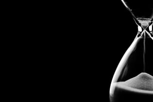 An image of an hourglass against a black background. 