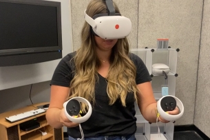 A student uses IUPUI's VR headset and joysticks to practice public speaking.