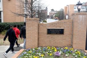 Three students walk past a plaque on a brick wall that reads "Morehouse College, founded 1867."